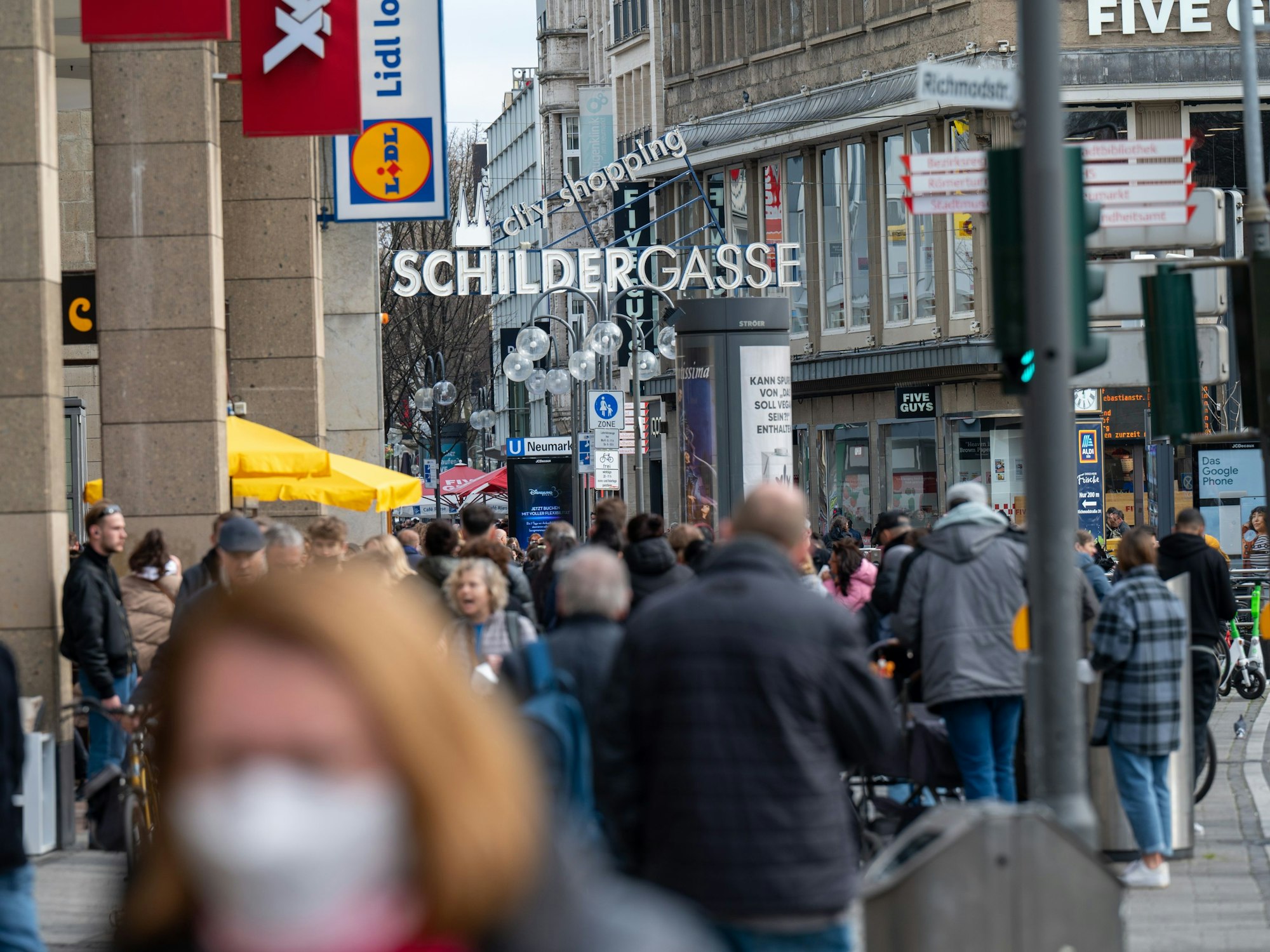 Die Schildergasse ist voller Menschen. Viele genießen das frühlingshafte Wetter im Freien.