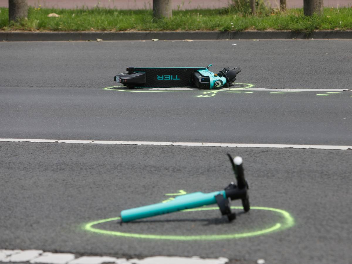 Zwei Teile eines verunfallten E-Scooters liegen auf der Rheinuferstraße in Köln.
