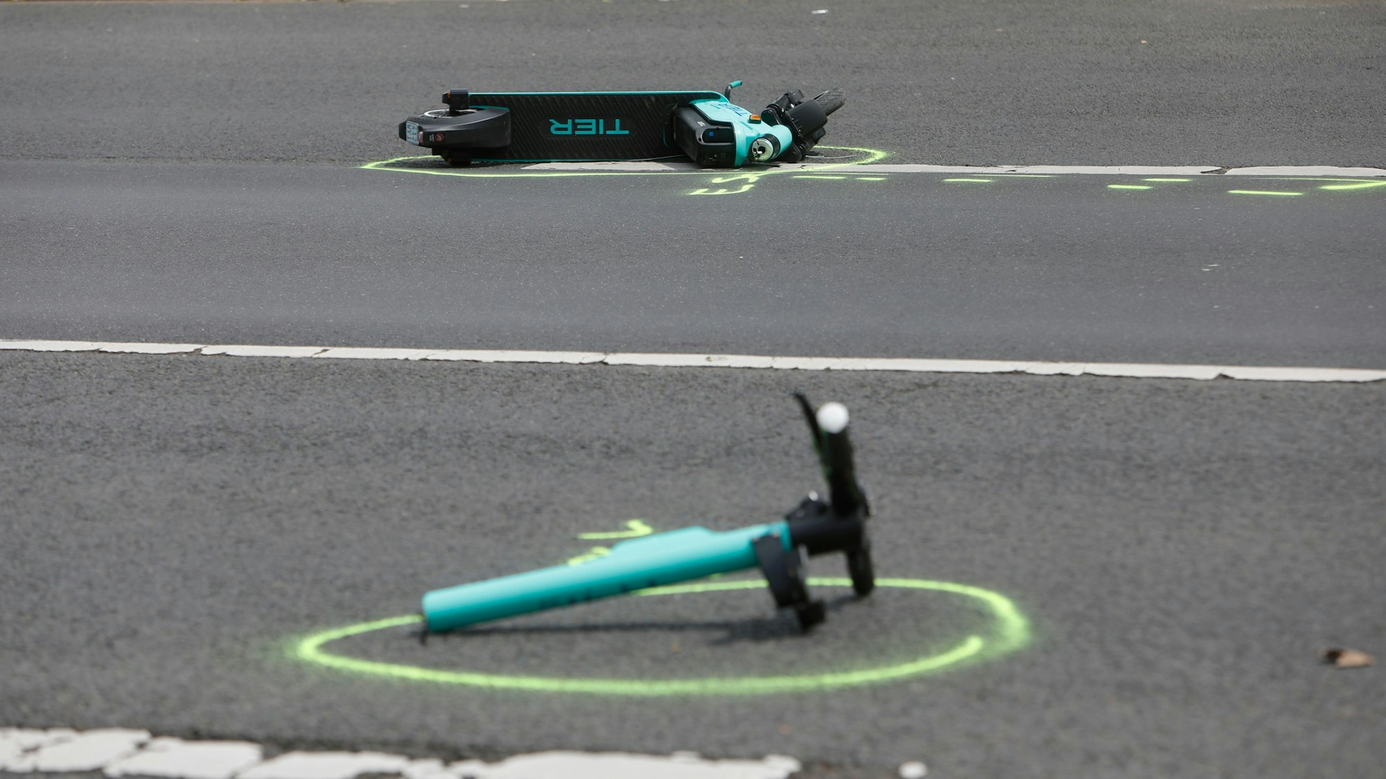 Ein in zwei Teile gebrochener E-Scooter liegt auf einer Fahrbahn.
