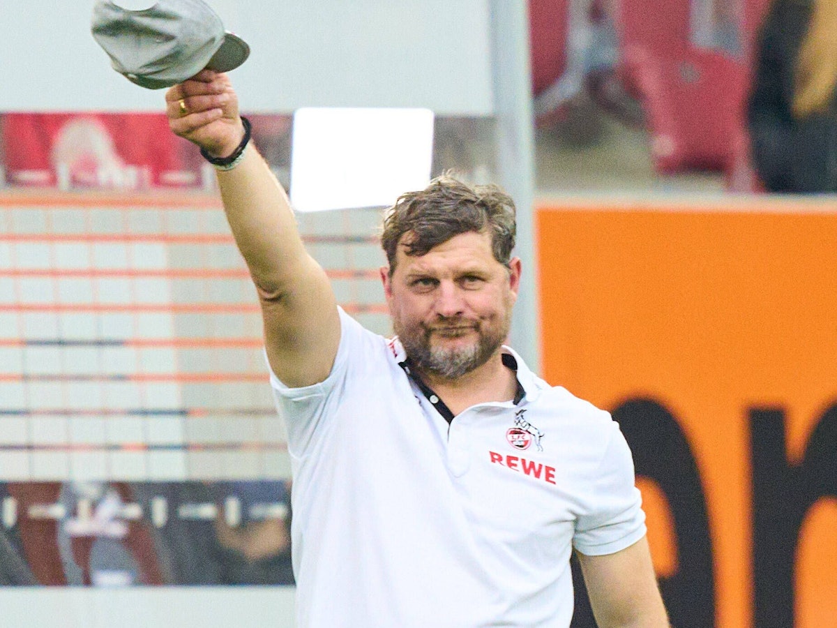 Steffen Baumgart zieht die Mütze vor der FC-Fankurve in Augsburg.