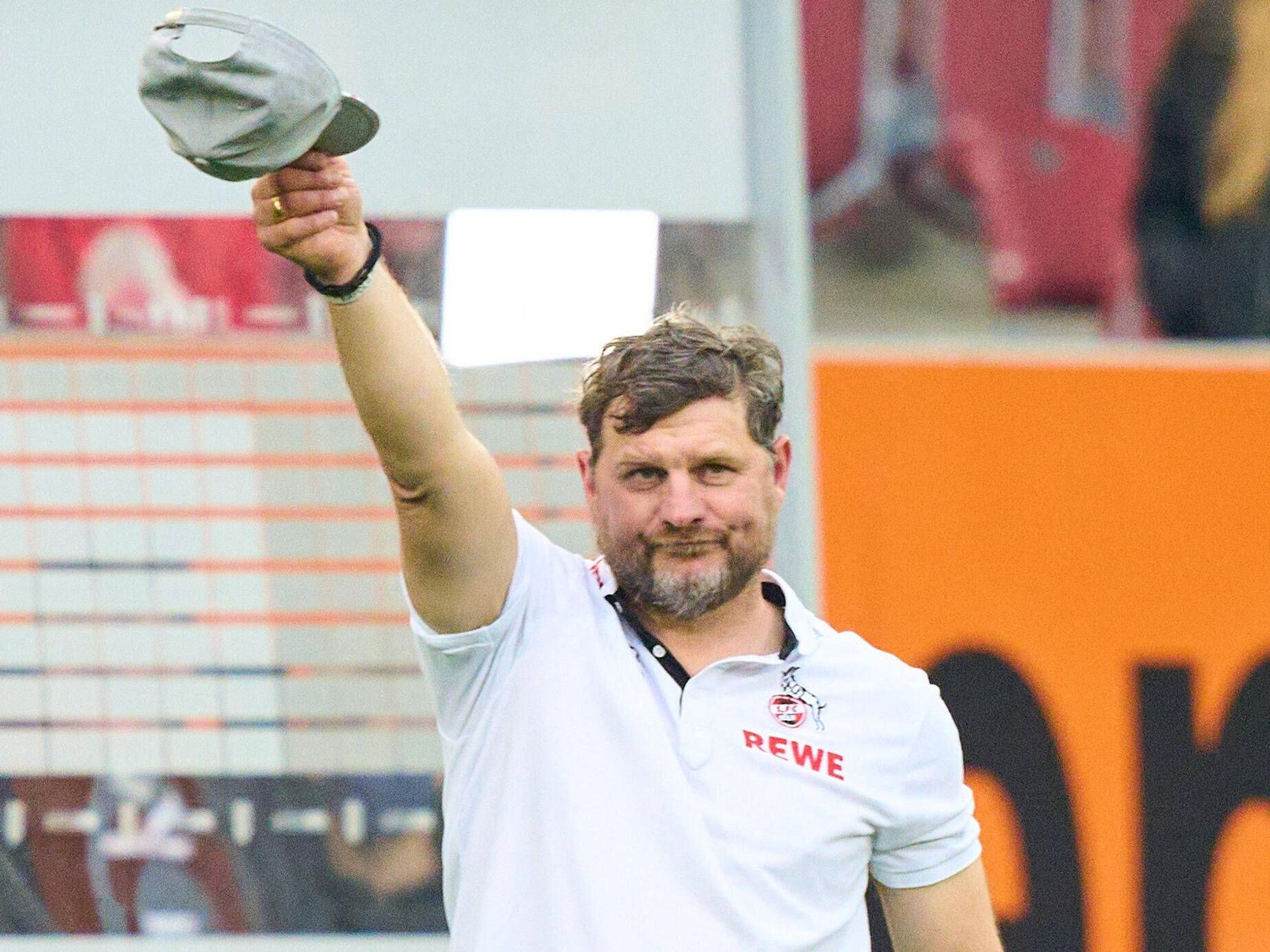 Steffen Baumgart zieht die Mütze vor der FC-Fankurve in Augsburg.