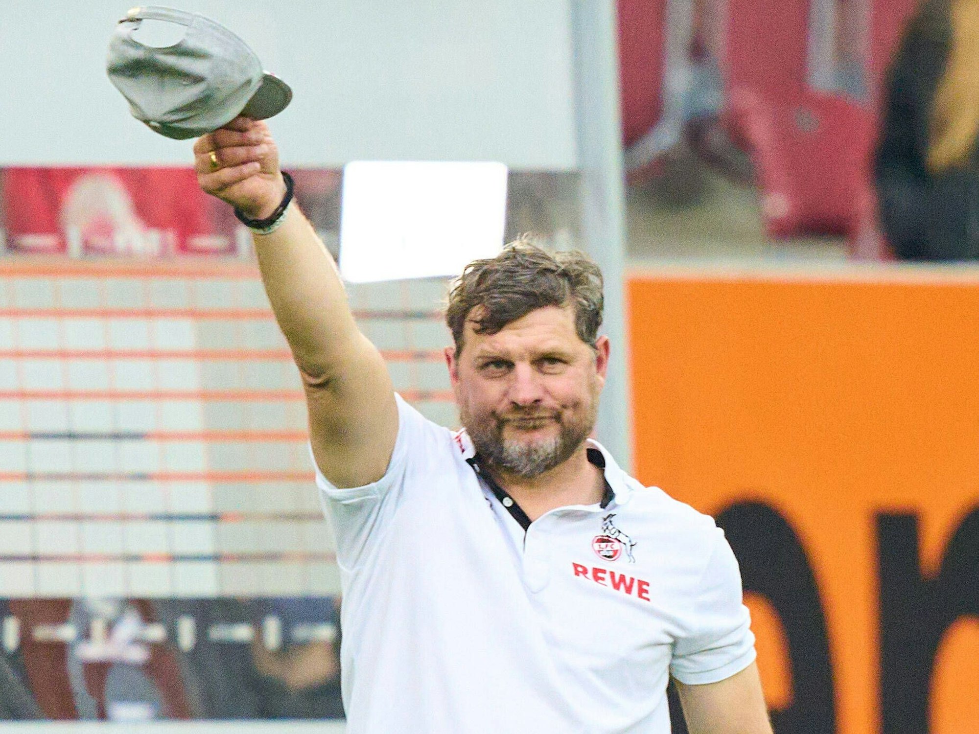 Steffen Baumgart zieht die Mütze vor der FC-Fankurve in Augsburg.