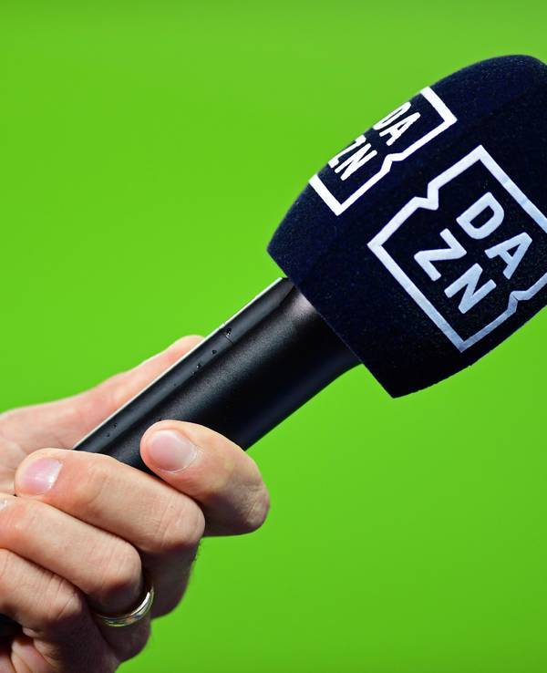 Die Hand eines Reporters hält bei einem Interview vor dem Spiel ein Mikrofon mit der Aufschrift DAZN.