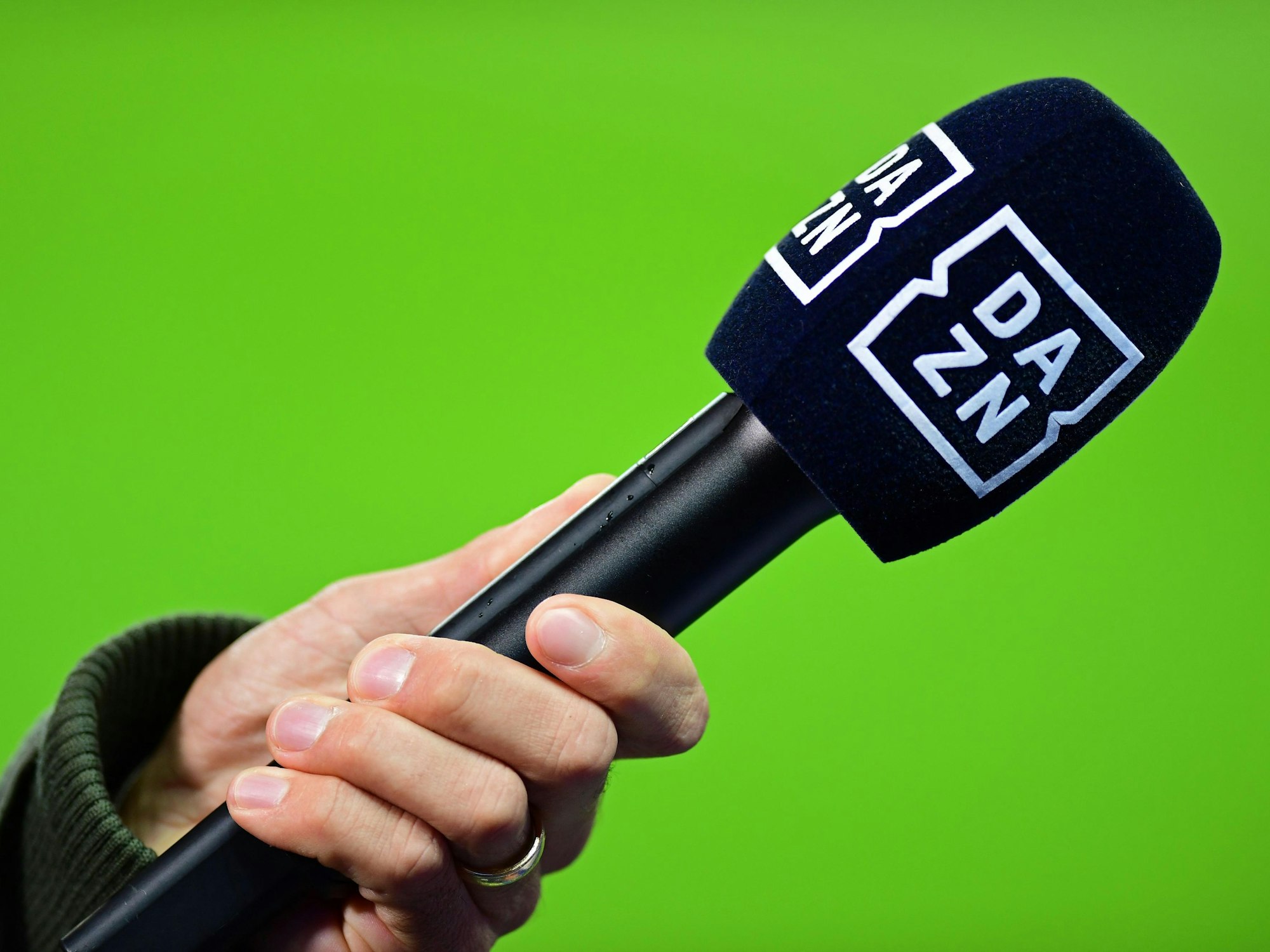 Die Hand eines Reporters hält bei einem Interview vor dem Spiel ein Mikrofon mit der Aufschrift DAZN.