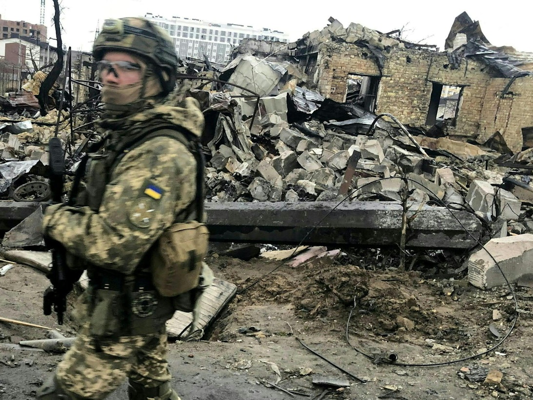 Das Bild zeigt einen ukrainischen Soldaten am 0. April 2022, der an den Trümmern zerstörter Häuser vorbeiläuft.