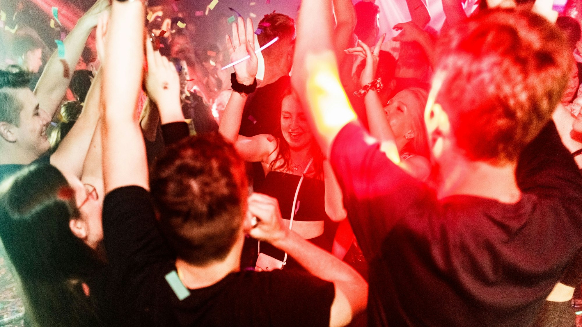 Besucherinnen und Besucher tanzen in einer Diskothek auf der Tanzfläche.