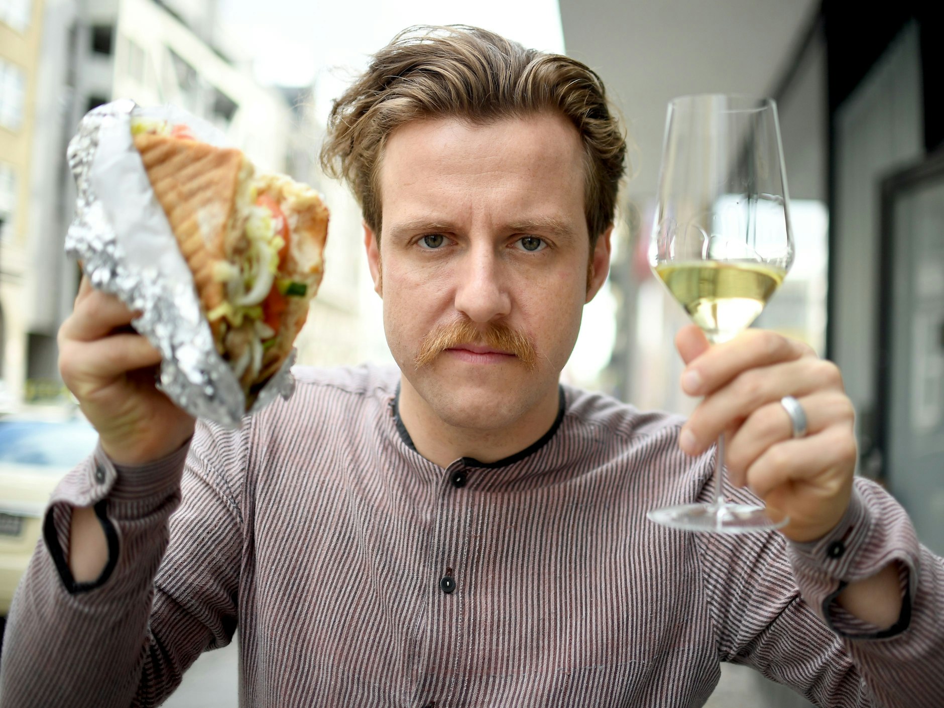 Sommelier Billy Wagner hält am 13.10.2017 in Berlin einen Döner und ein Glas Wein in der Hand.