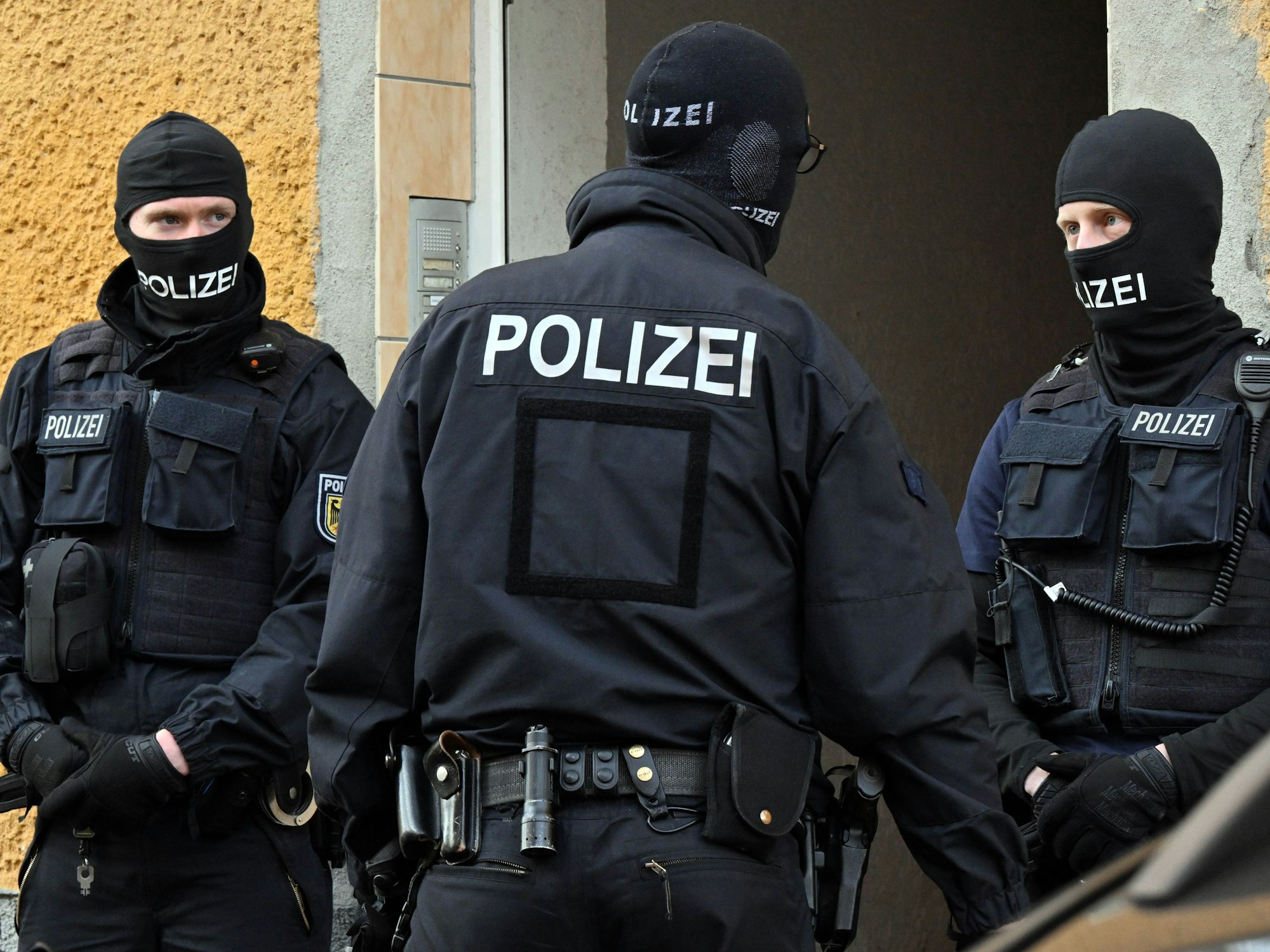 Bundespolizisten stehen vor einem Hauseingang.