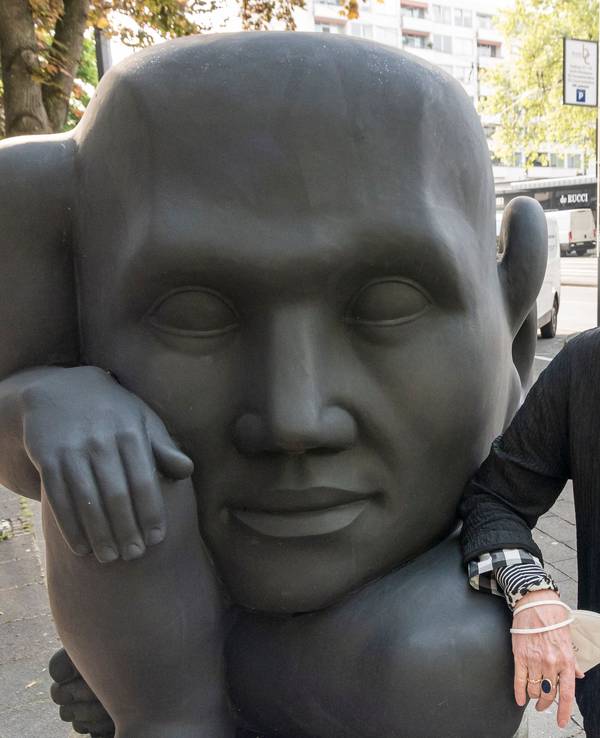 Inhaberin Angelika Herzogenrath neben der schwarzen Skulptur „In die Zukunft horchend“ von Michael Schwarze, die seit 2010 vor der Kölner Kunsthandlung Goyert steht.