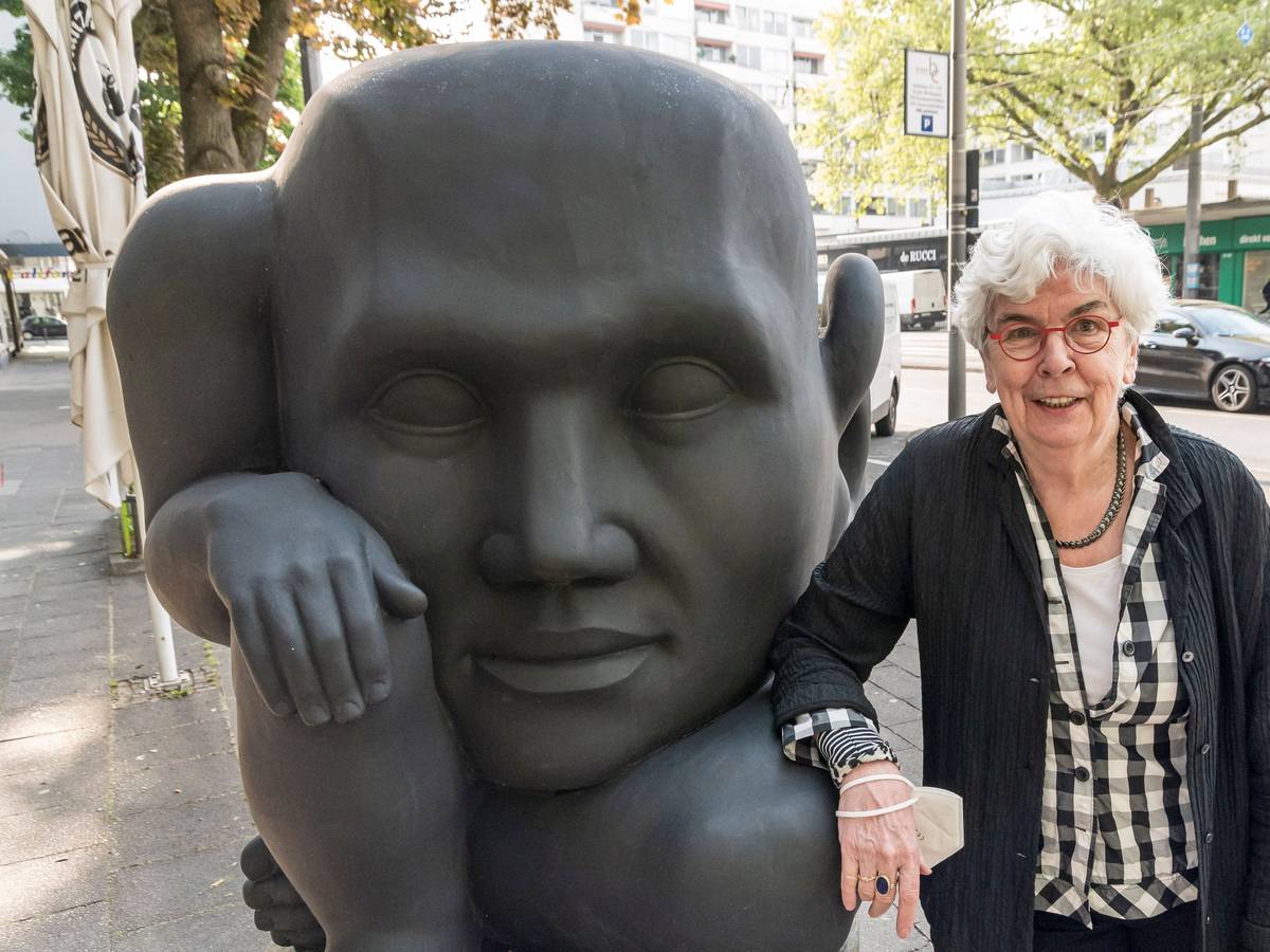Inhaberin Angelika Herzogenrath neben der schwarzen Skulptur „In die Zukunft horchend“ von Michael Schwarze, die seit 2010 vor der Kölner Kunsthandlung Goyert steht.