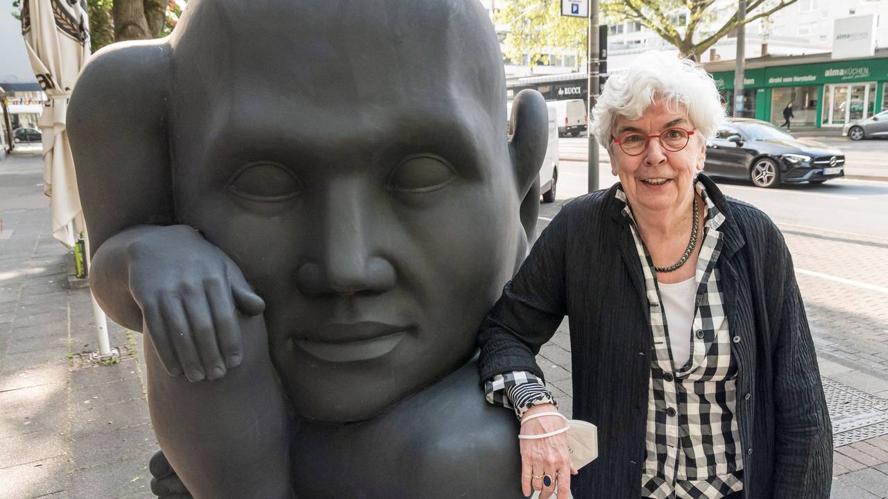 Inhaberin Angelika Herzogenrath neben der schwarzen Skulptur „In die Zukunft horchend“ von Michael Schwarze, die seit 2010 vor der Kölner Kunsthandlung Goyert steht.