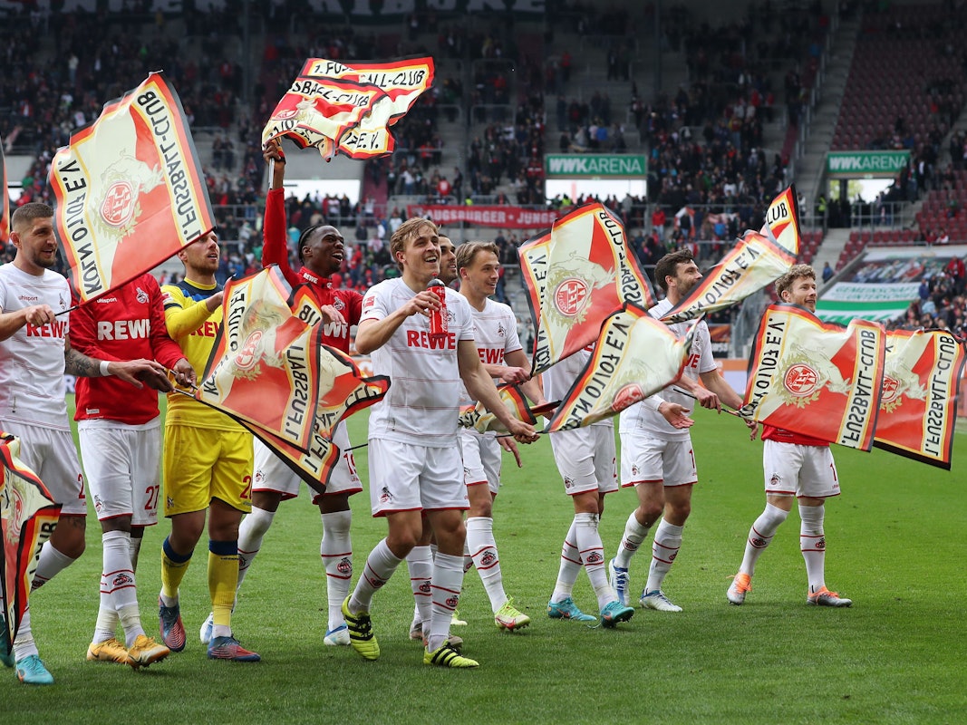 Nach dem Sieg in Augsburg feiern die FC-Profis mit Fähnchen in der Fankurve.
