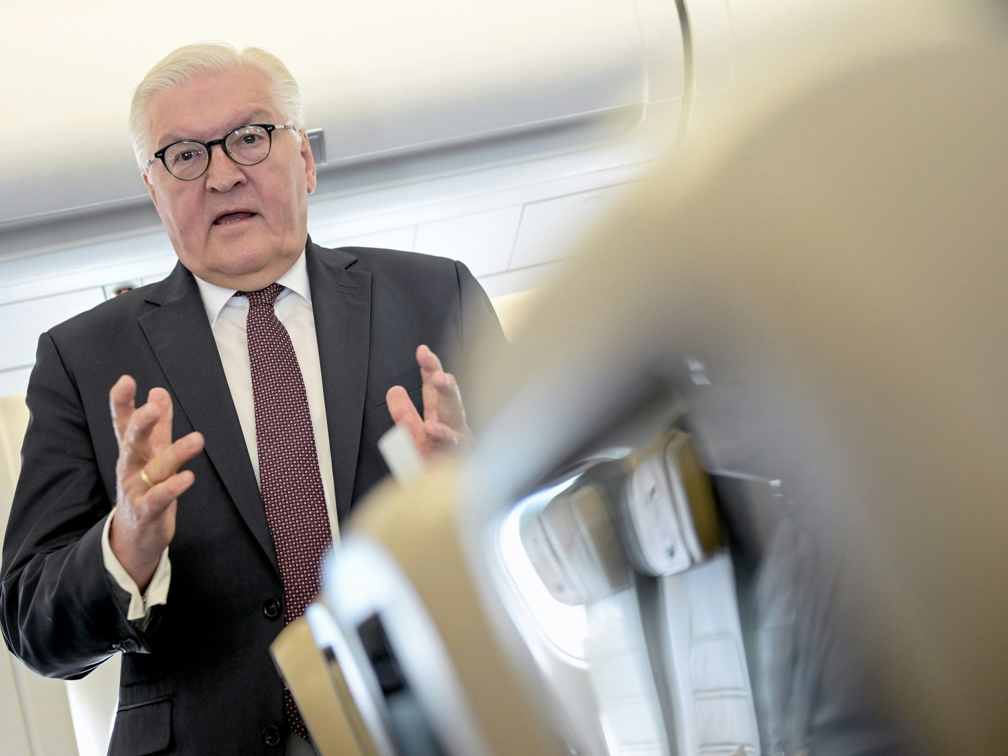 Bundespräsident Frank-Walter Steinmeier spricht im Anzug auf dem Flug am 4. Mai 2022 nach Rumänien.