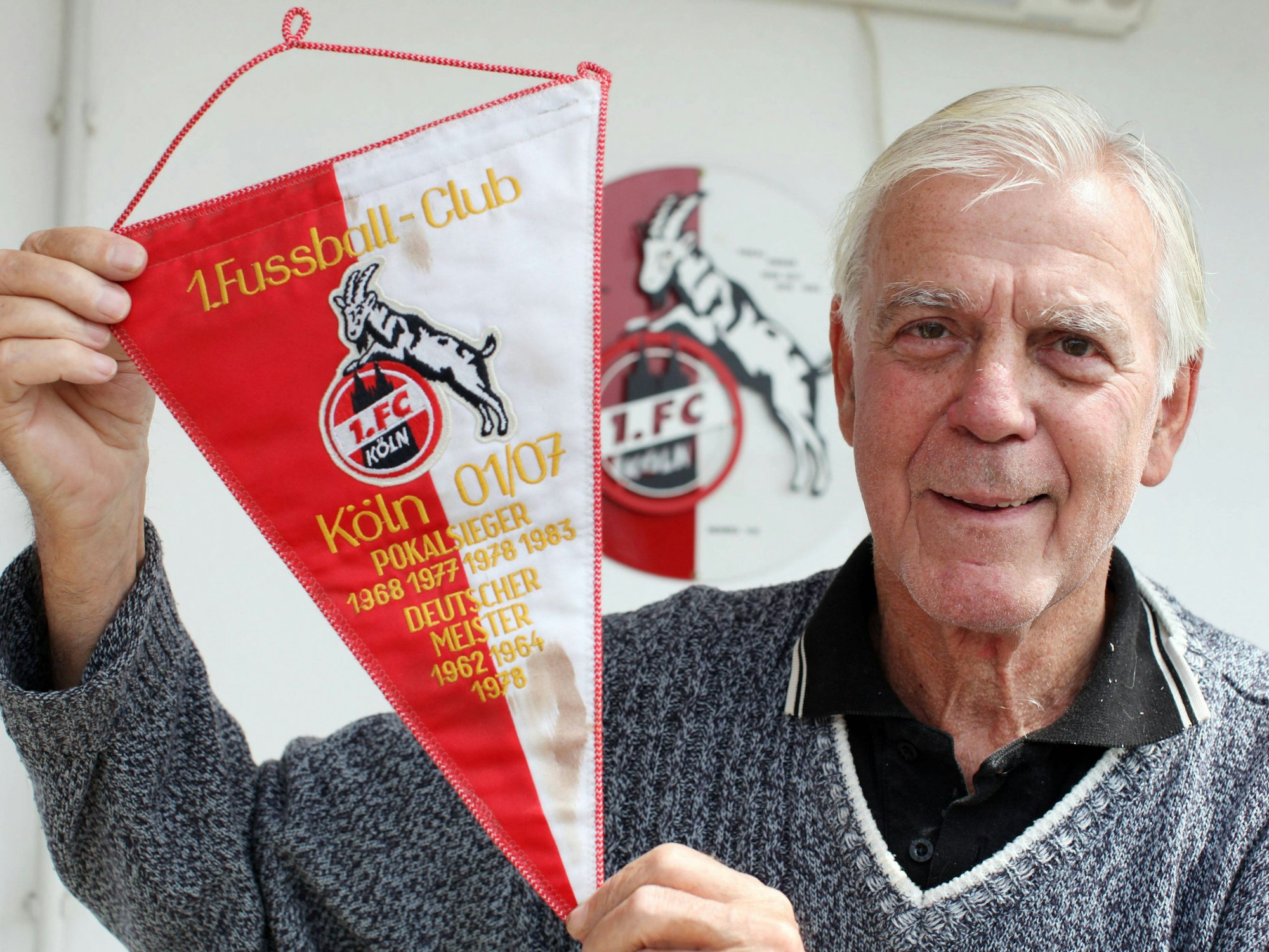 Leo Wilden hält einen Wimpel des 1. FC Köln in die Kamera.