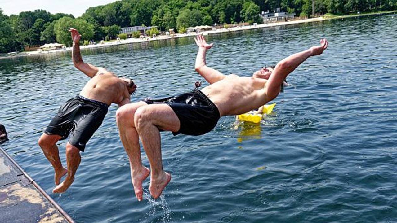 Zwei junge Männer springen am 18. Juni 2021 in den Fühlinger See.