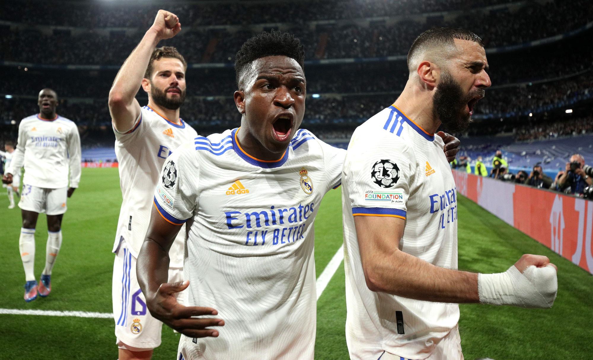 Karim Benzema (r.) jubelt mit Vinicius Junior (Mitte) und Nacho Fernandes über seinen verwandelten Elfmeter zum 3:1.