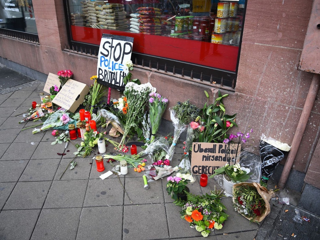 Blumen, Kerzen und Schilder liegen und stehen an dem Ort, an dem am Montag (2. Mai 2022) ein Mann nach einer Polizeikontrolle gestorben ist.