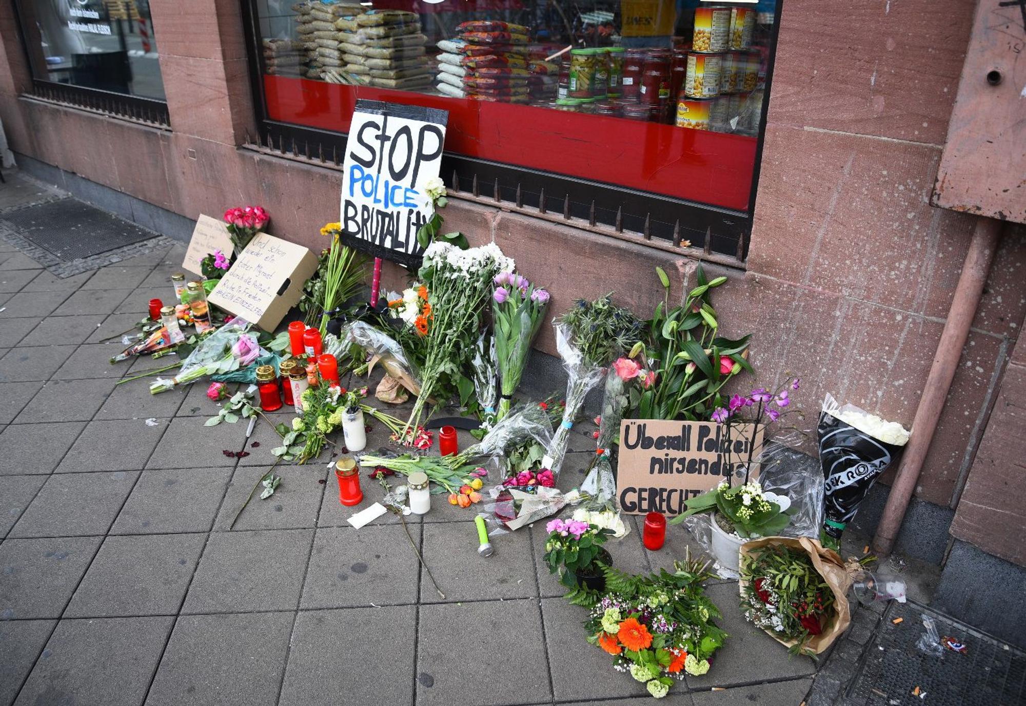 Blumen, Kerzen und Schilder liegen und stehen an dem Ort, an dem am Montag (2. Mai 2022) ein Mann nach einer Polizeikontrolle gestorben ist.