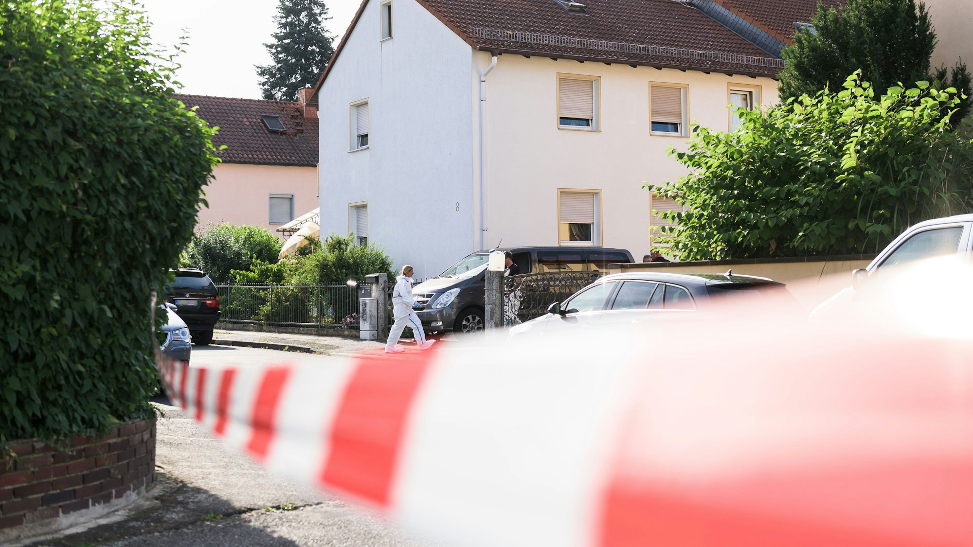 Eine Mitarbeiterin der Spurensicherung steht vor einem Einfamilienhaus.
