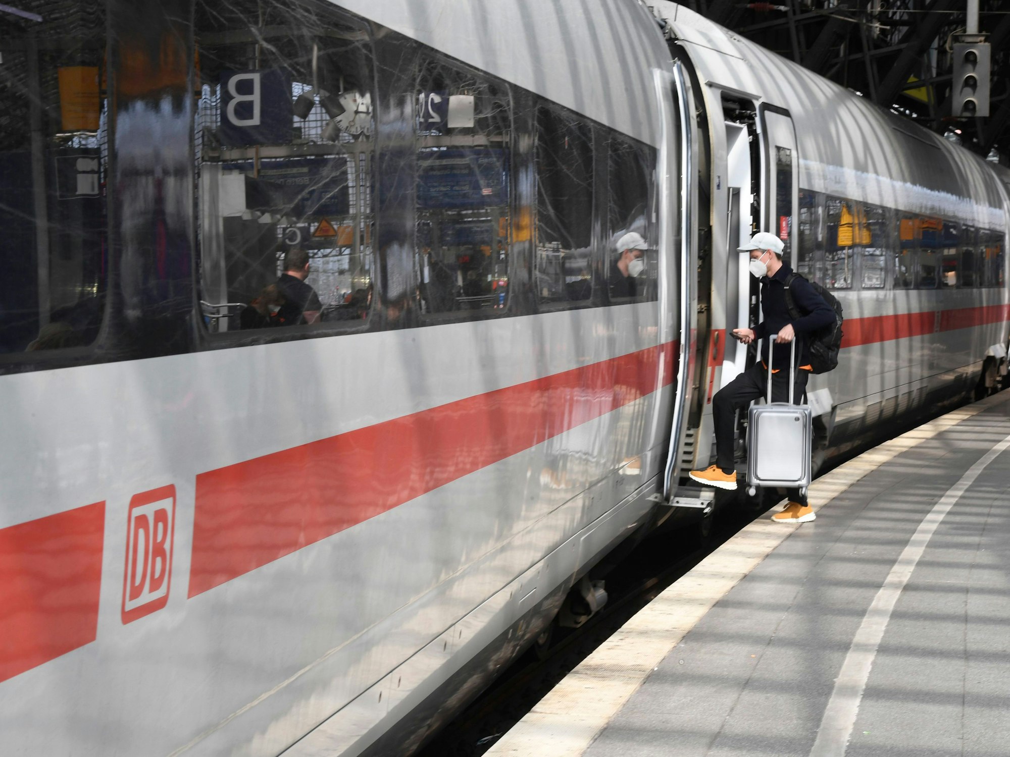 Ein Reisender steigt an Bahnsteig im Kölner Hauptbahnhof in einen Zug.