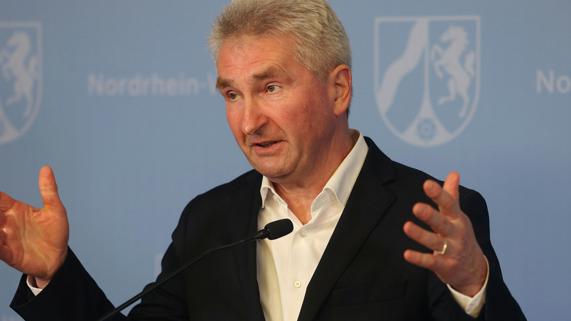 Andreas Pinkwart (FDP) mit erhobenen Händen im Anzug bei einer Rede am 21. Februar 2022.