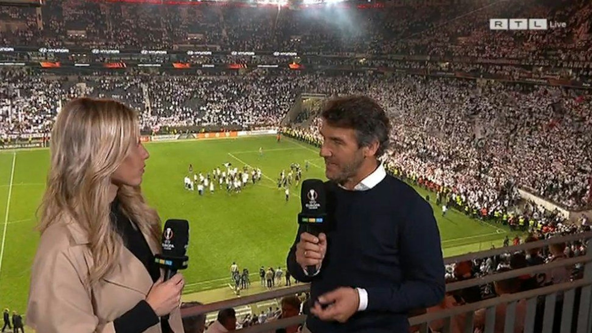 RTL: Moderatorin Laura Papendick und Karl-Heinz Riedle auf der Tribüne.