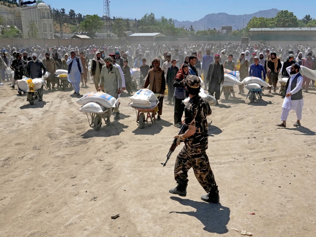 Die Taliban schreiben Frauen in Afghanistan eine Burka in der Öffentlichkeit vor. Unser Foto zeigt einen Taliban-Kämpfer, der Ende April Wache steht, während Menschen Lebensmittelrationen erhalten.