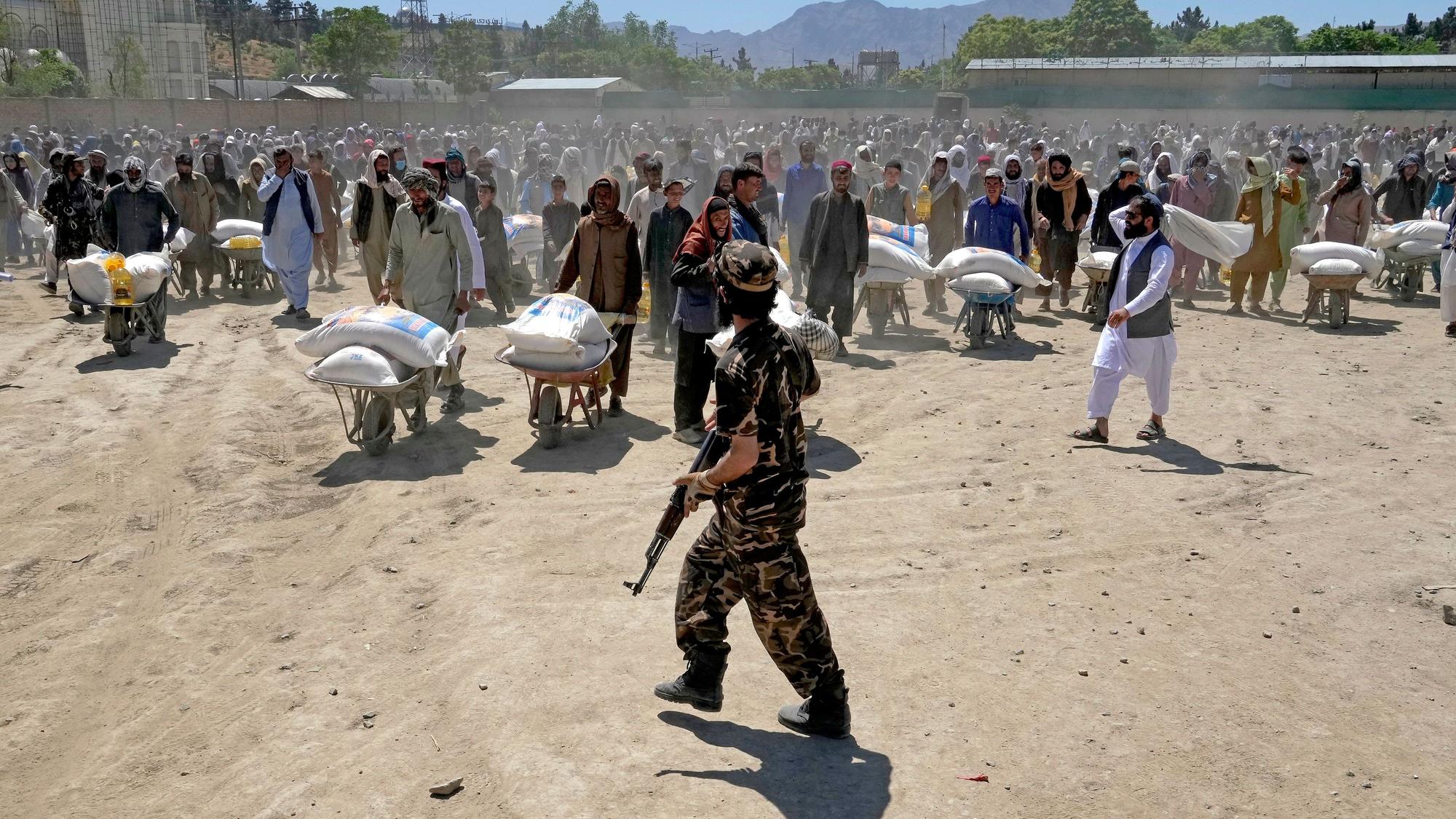 Die Taliban schreiben Frauen in Afghanistan eine Burka in der Öffentlichkeit vor. Unser Foto zeigt einen Taliban-Kämpfer, der Ende April Wache steht, während Menschen Lebensmittelrationen erhalten.
