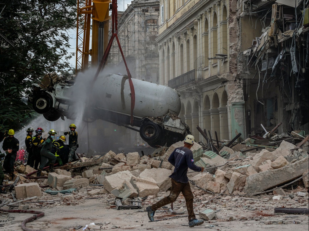06.05.2022, Kuba, Havanna: Feuerwehrleute besprühen einen Tankwagen mit Wasser, um ihn zu kühlen, während sie ihn vom Ort einer tödlichen Explosion entfernen, die das Fünf-Sterne-Hotel Saratoga in Havanna, Kuba, zerstört hat.