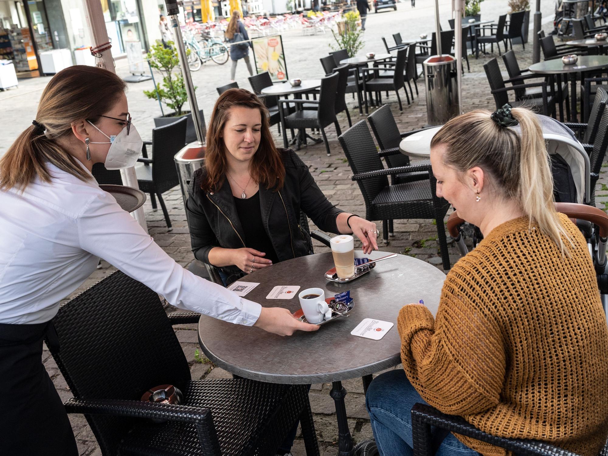 Sarah Borgholte (M) und Angelique Paul-Brackelmann (r) bekommen vor der Brasserie „Lamäng“ ihren Kaffee serviert.