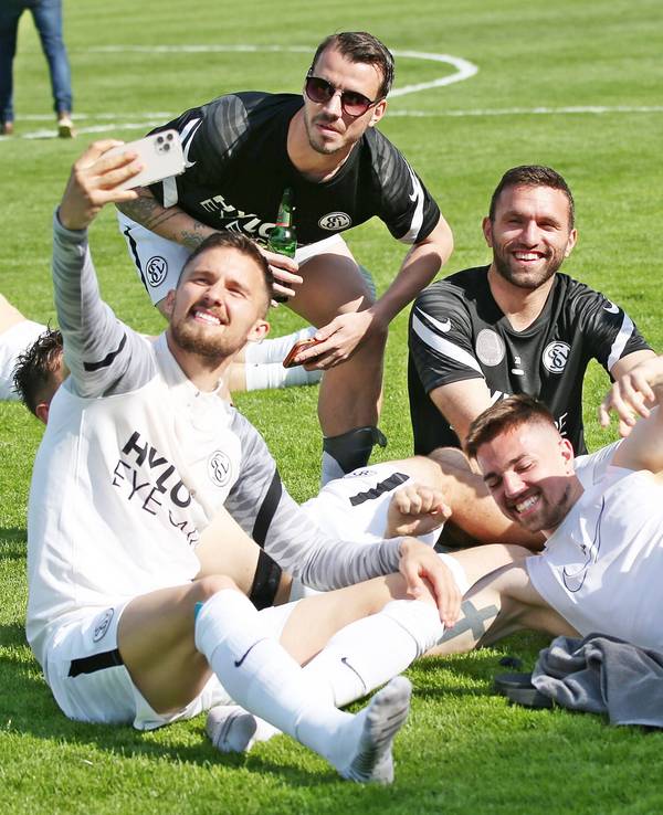 Spieler von der SV Elversberg sitzen auf dem Rasen.