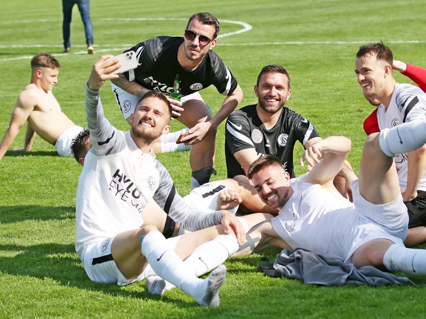 Spieler von der SV Elversberg sitzen auf dem Rasen.