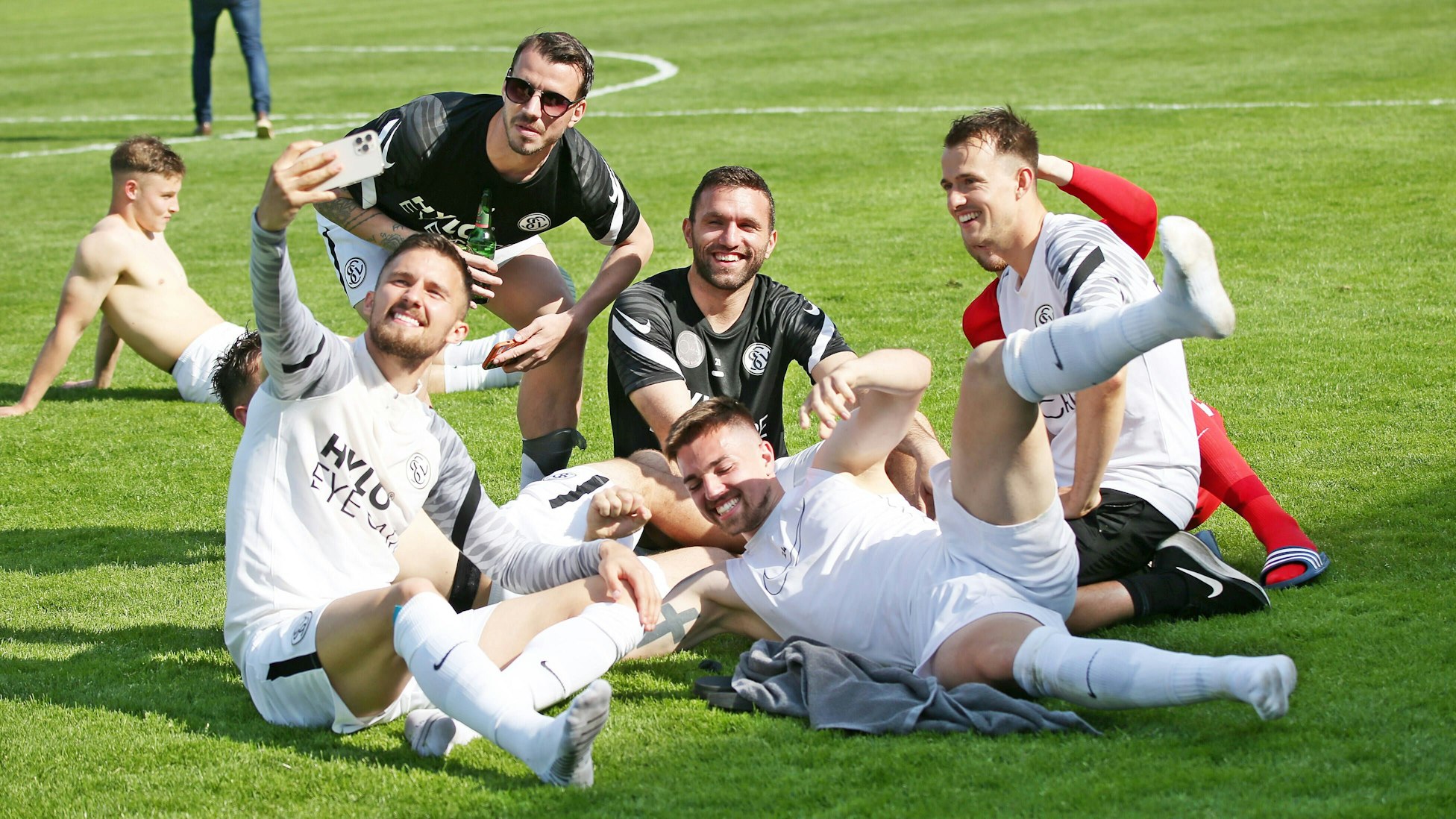 Spieler von der SV Elversberg sitzen auf dem Rasen.