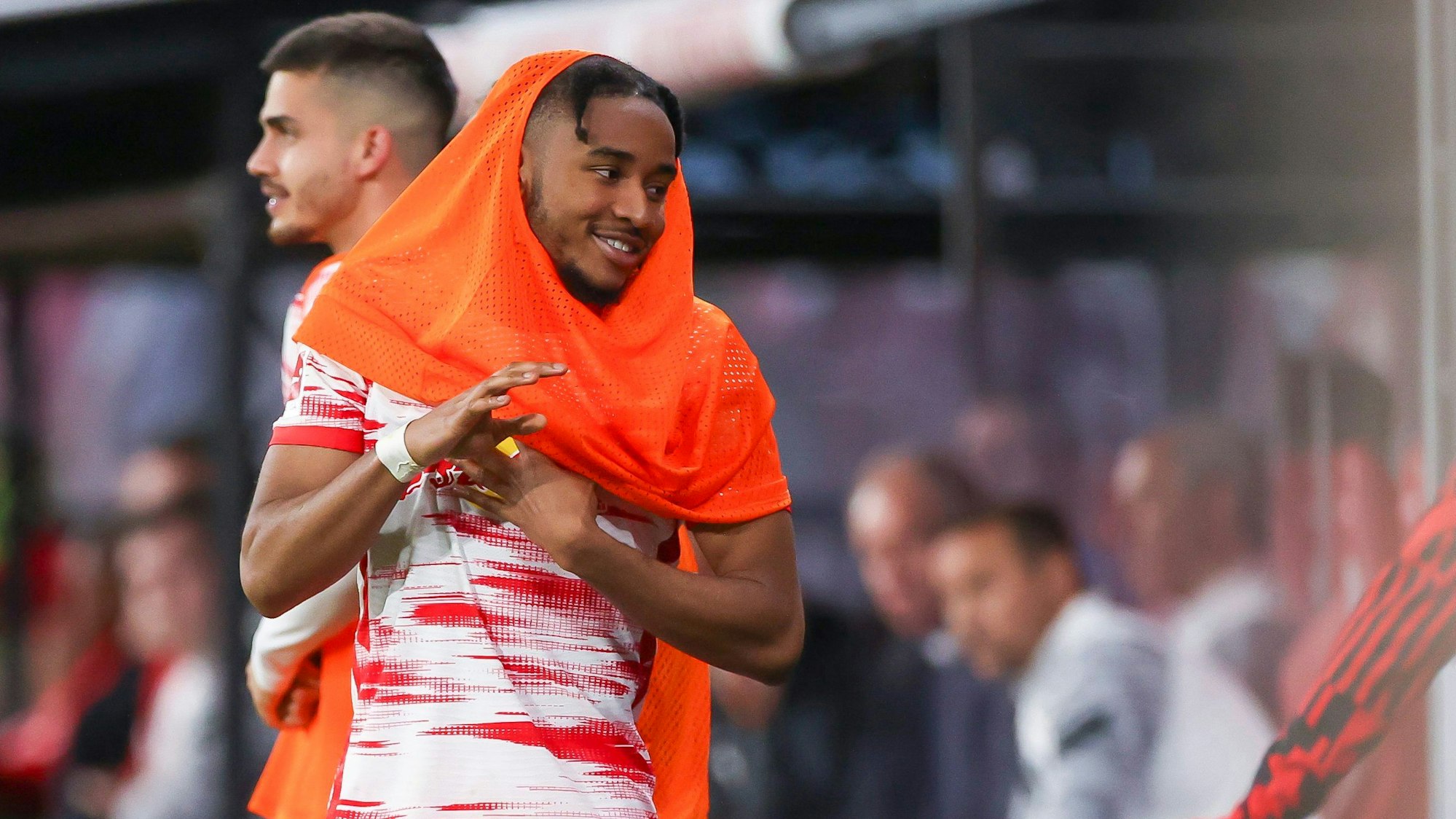 Leipzigs Spieler Christopher Nkunku steht mit einem Leibchen über dem Kopf an der Bande.