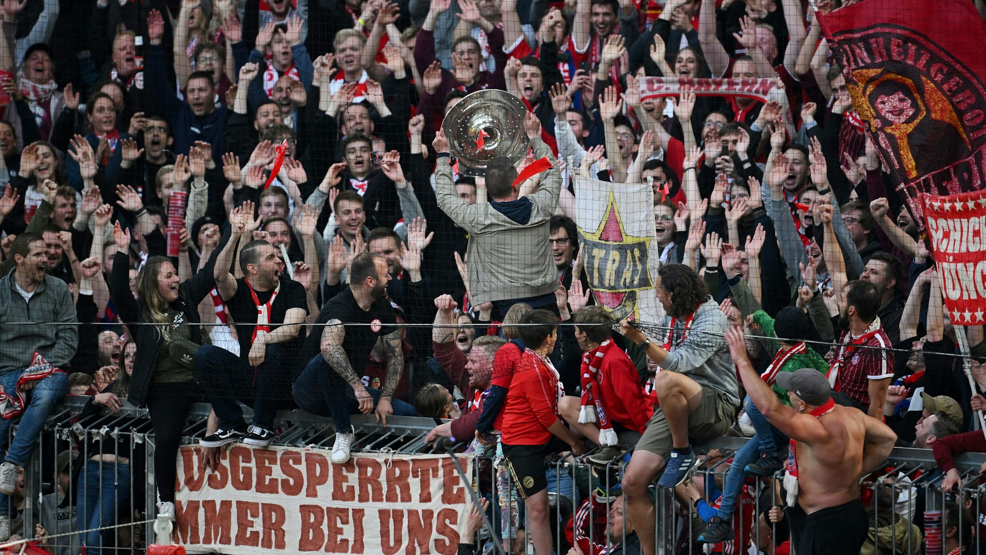 Fans des FC Bayern München feiern mit der Meisterschale.