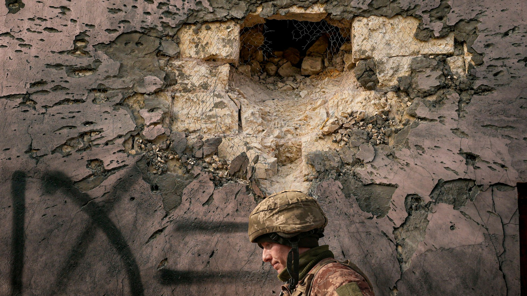 Ein ukrainischer Soldat geht an einem Gebäude vorbei, das von einer großkalibrigen Mörsergranate im Frontdorf Krymske in der Region Luhansk in der Ostukraine getroffen wurde.