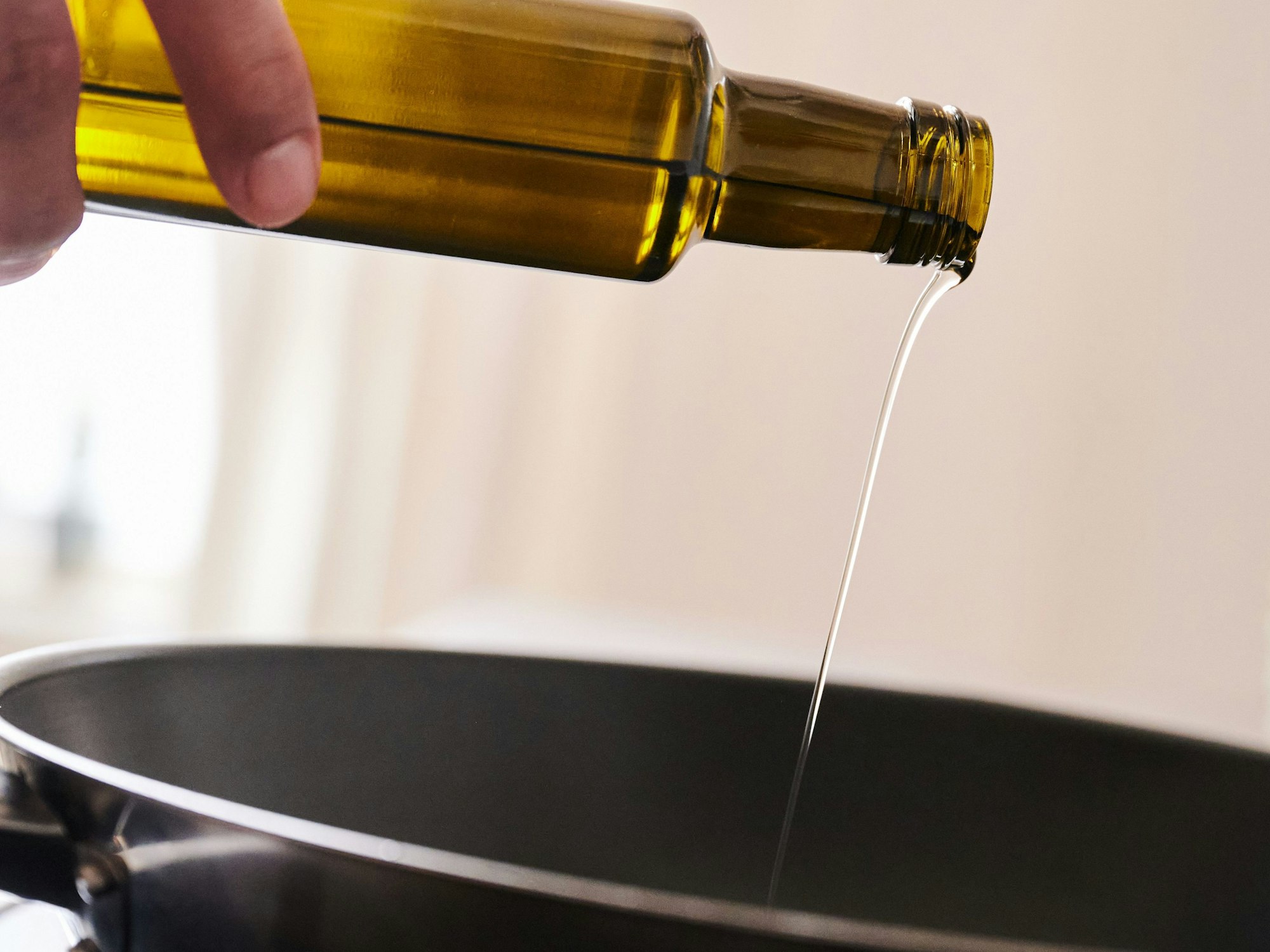 Ein Mann schüttet Sonnenblumenöl in eine Pfanne.