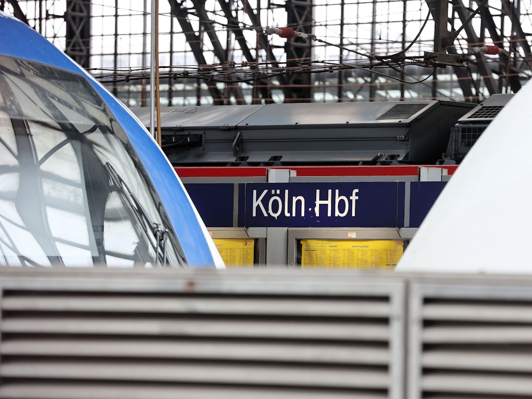 Schild am Hauptbahnhof Köln, davor Züge.