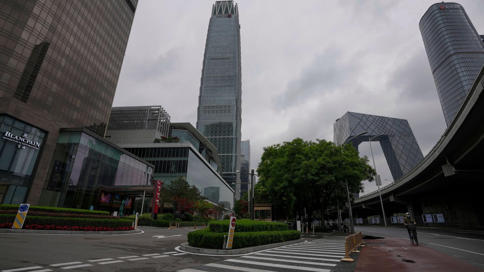 Ein Mann fährt auf einem Fahrrad an einer ruhigen Straße in der Nähe des verschlossenen China World Trade Center vorbei.