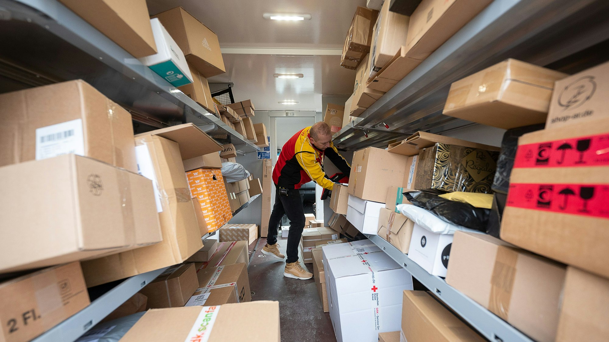Ein DHL-Mitarbeiter sortiert am 15. Dezember 2021 in seinem Transporter die Pakete und Päckchen für die nächsten Zustellungen