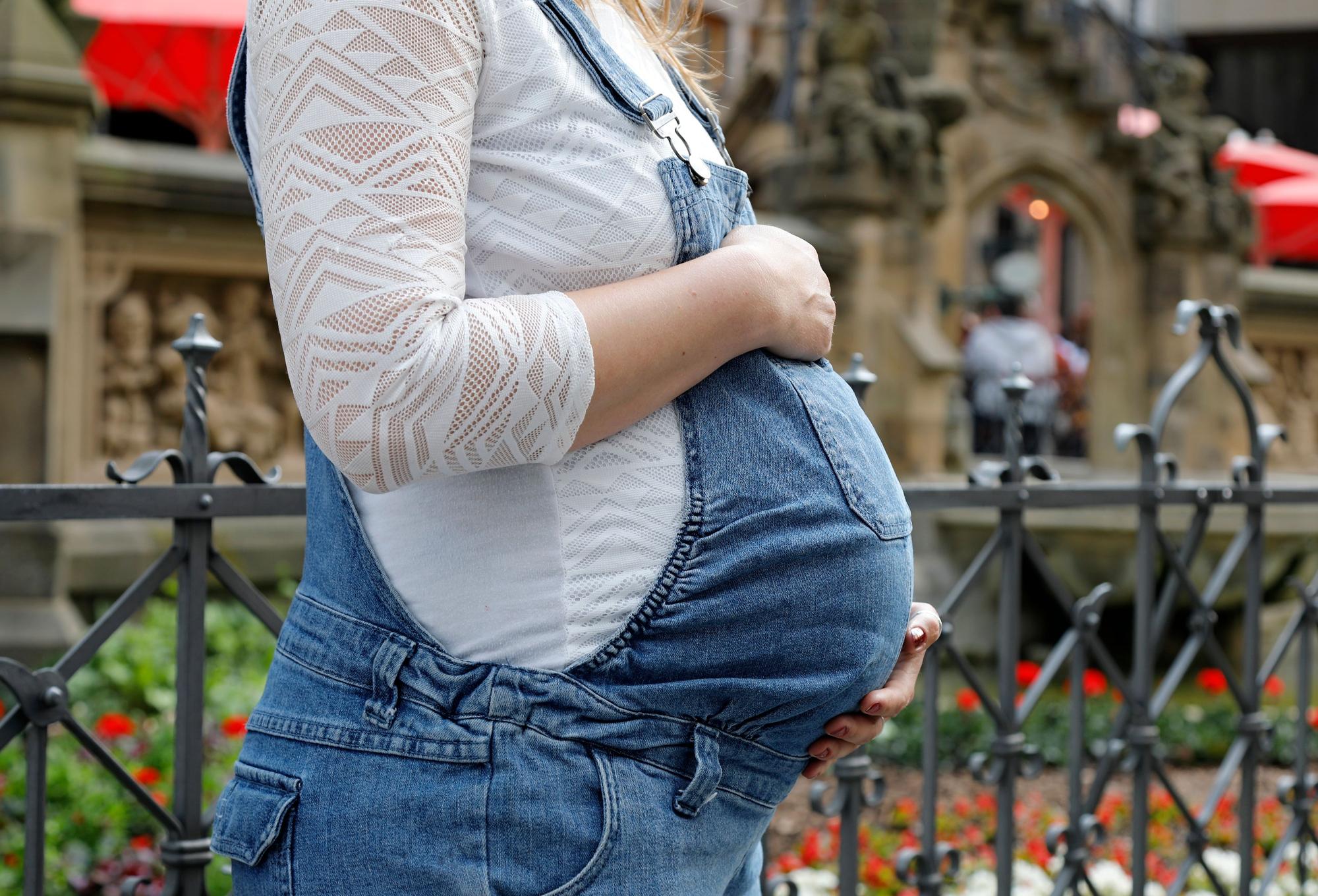 Eine schwangere Frau mit Babybauch von der Seite fotografiert