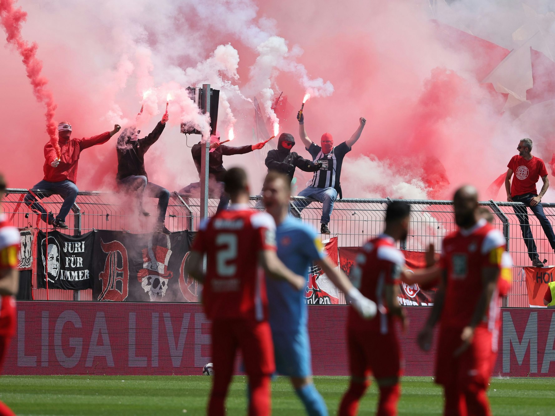 Fans zünden Benaglos im Hintergrund vor einem Fußballspiel.