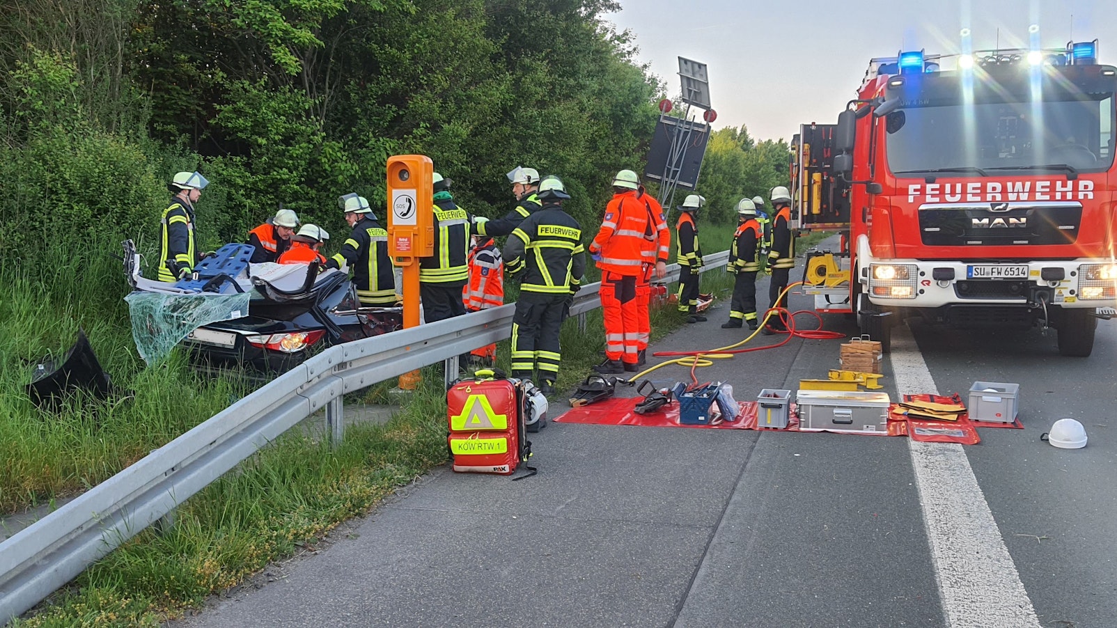 Auto steht nach Unfall neben A3, Feuerwehr mit mehreren Fahrzeugen vor Ort.