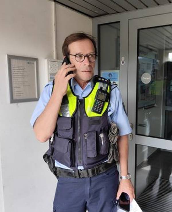 Polizist Sven Bartz telefoniert in einem Hauseingang.