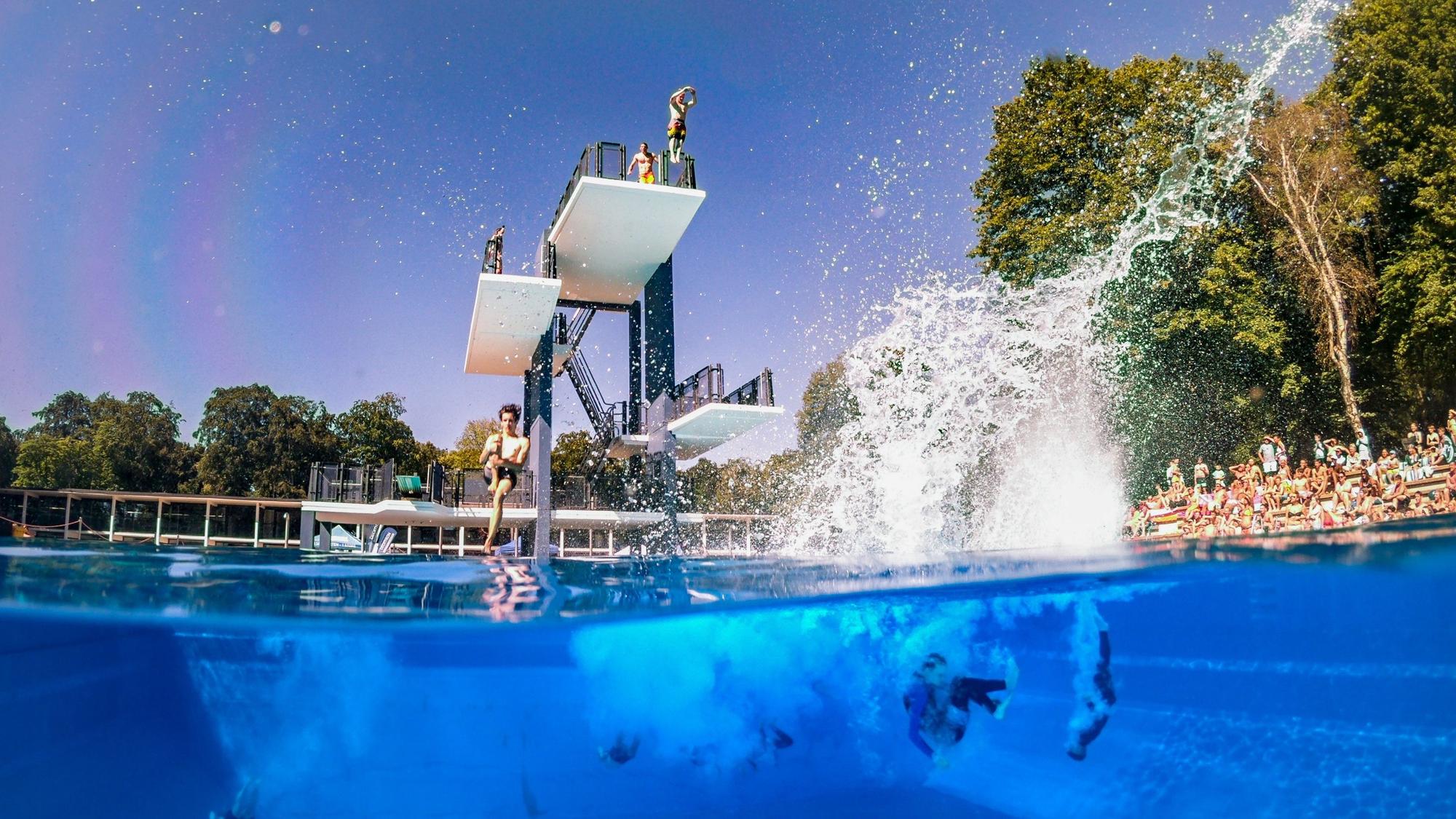 Turmspringer springen im Kölner Stadionbad ins Wasser.