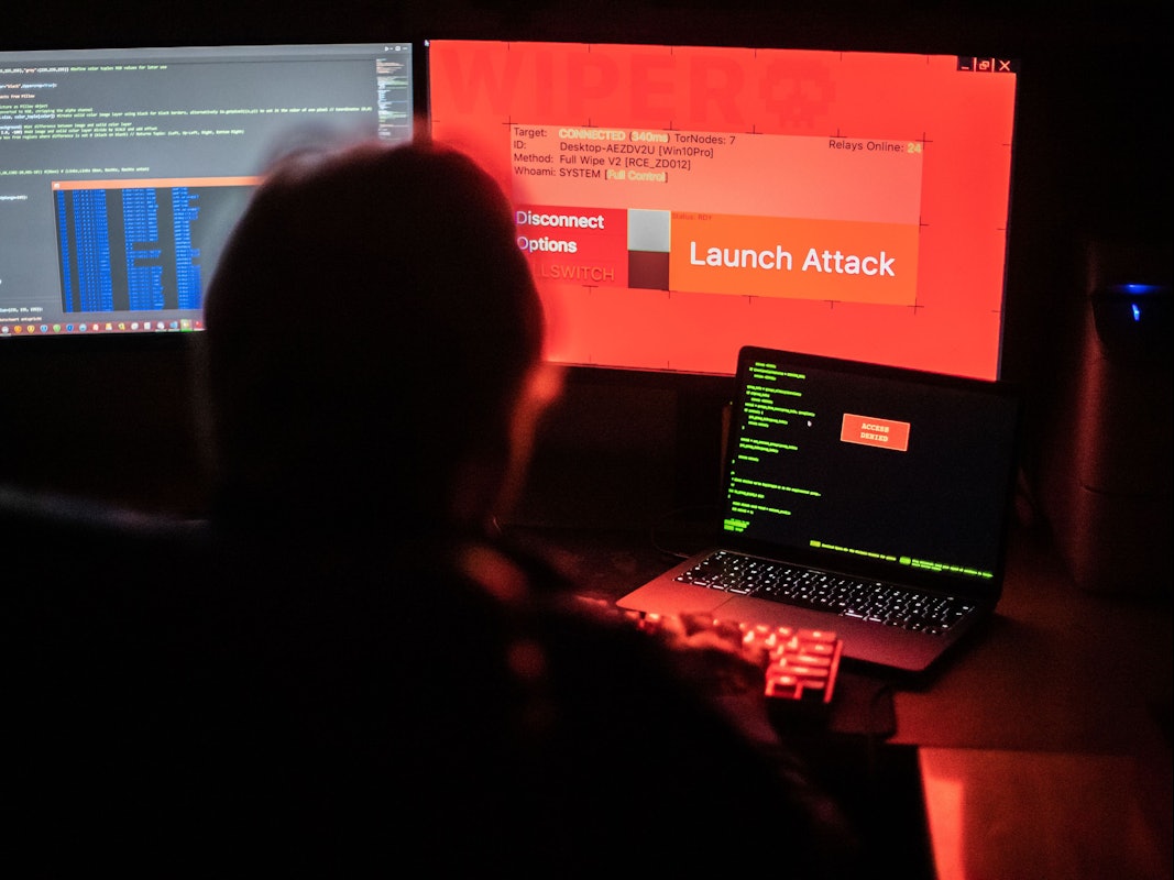 Das Symbolfoto vom 25.02.2022 aus Bad Oeynhausen (NRW) zeigt einen Mann vor Bildschirmen, die Hacker-Programme und eine fiktive Fernlösch-Software zeigen.