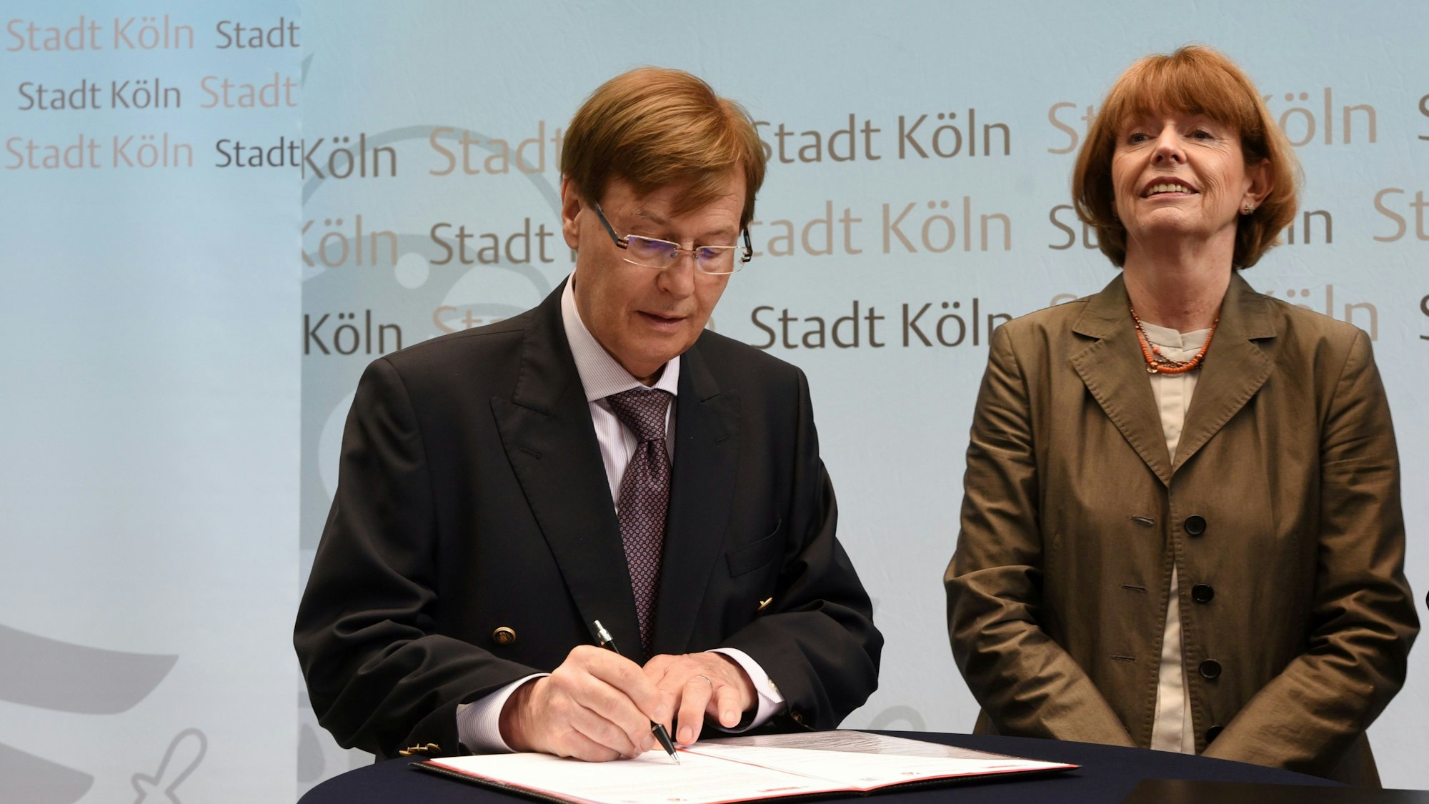 NRW-Justizminister Peter Biesenbach und Kölns OB Henriette Reker unterzeichnen ein Papier.