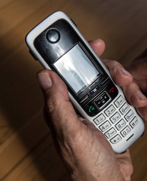Symbolbild: Ein älterer Mann hält am 29. April 2021 ein kabelloses Festnetztelefon in der Hand.
