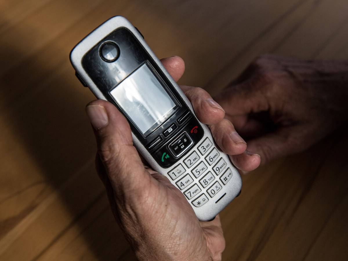 Symbolbild: Ein älterer Mann hält am 29. April 2021 ein kabelloses Festnetztelefon in der Hand.