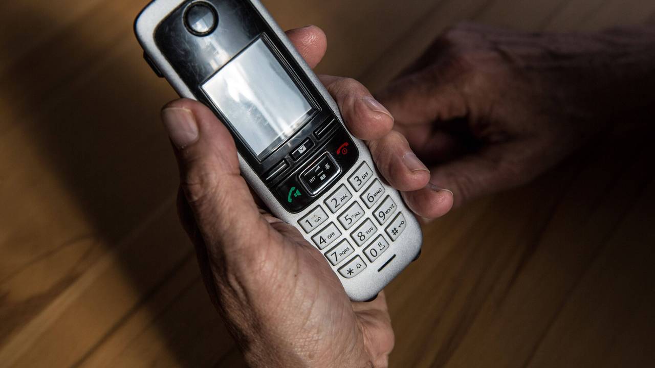 Symbolbild: Ein älterer Mann hält am 29. April 2021 ein kabelloses Festnetztelefon in der Hand.
